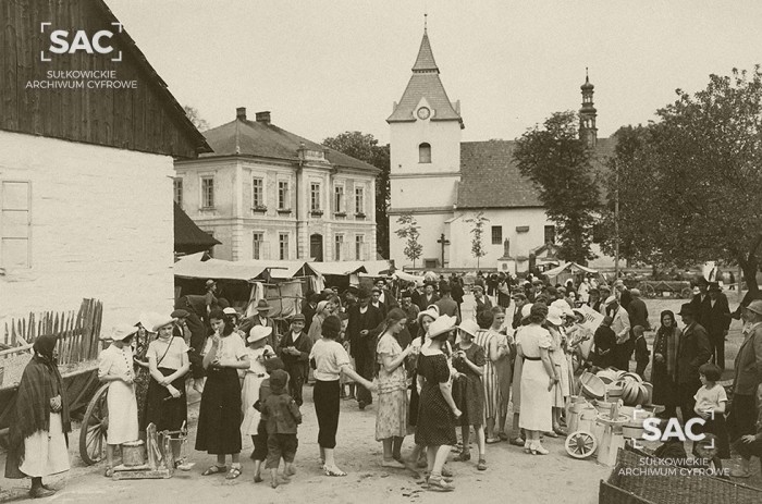 Sułkowice z lat 30 XX w. w obiektywie Stanisława Muchy. Fotografia pochodzi z Albumu kolonii letniej dla dziewcząt w Harbutowicach z daru Aleksandry Leśnodorskiej. Na fotografii widoczny rynek podczas targu, budynek szkoły i nieistniejący już kościół.